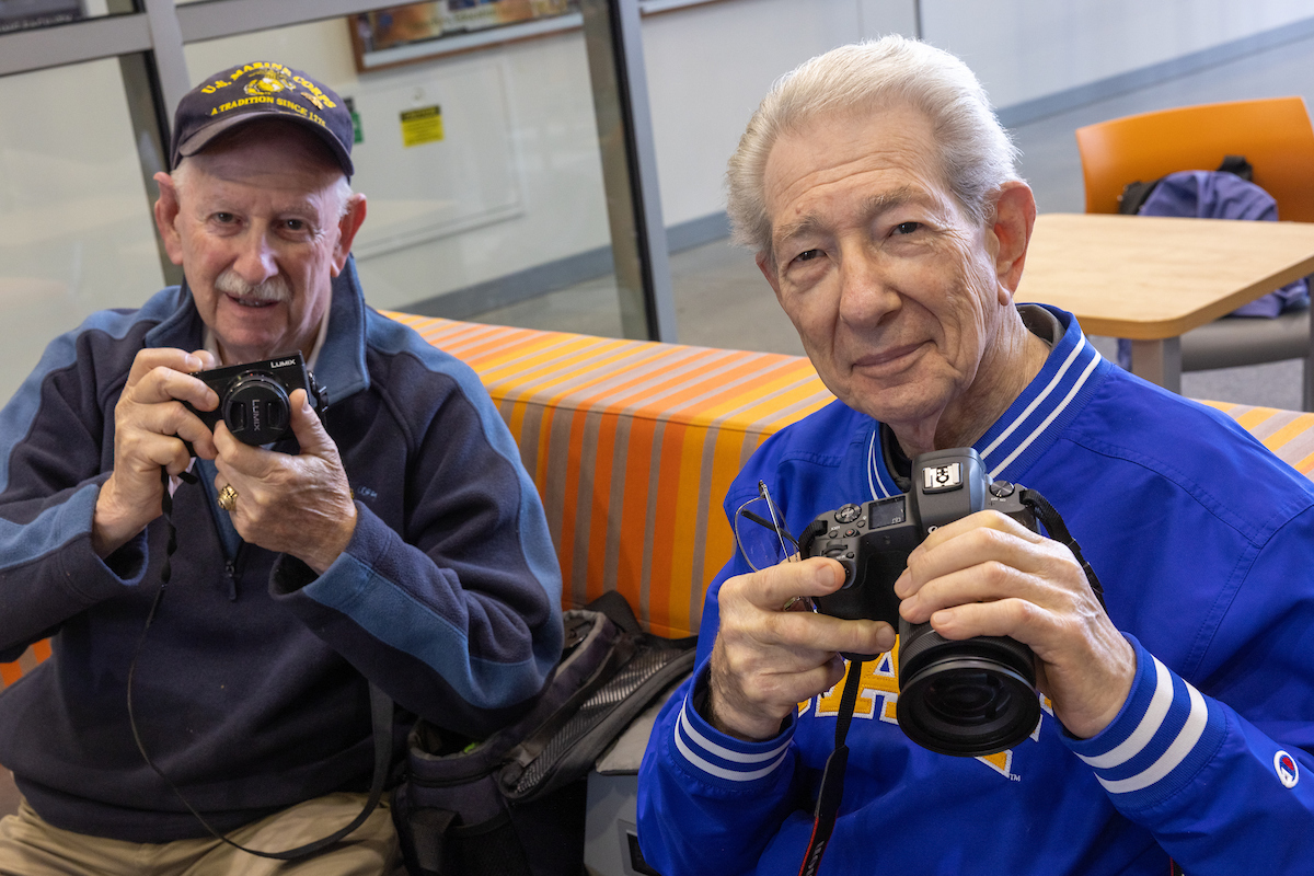 UAF Alumnus Ron Fayer ('62), right, and his brother Stan Fayer, left, pose with their cameras while taking photos as UAF Alumni stop by the Joseph E. Usibelli Building Atrium to visit after lunch and meet Yogi, the new UAF Campus Police K9 officer, during the Annual Nanook Rendezvous Alumni Reunion Campus Day on the UAF campus Friday afternoon, July 14, 2023.