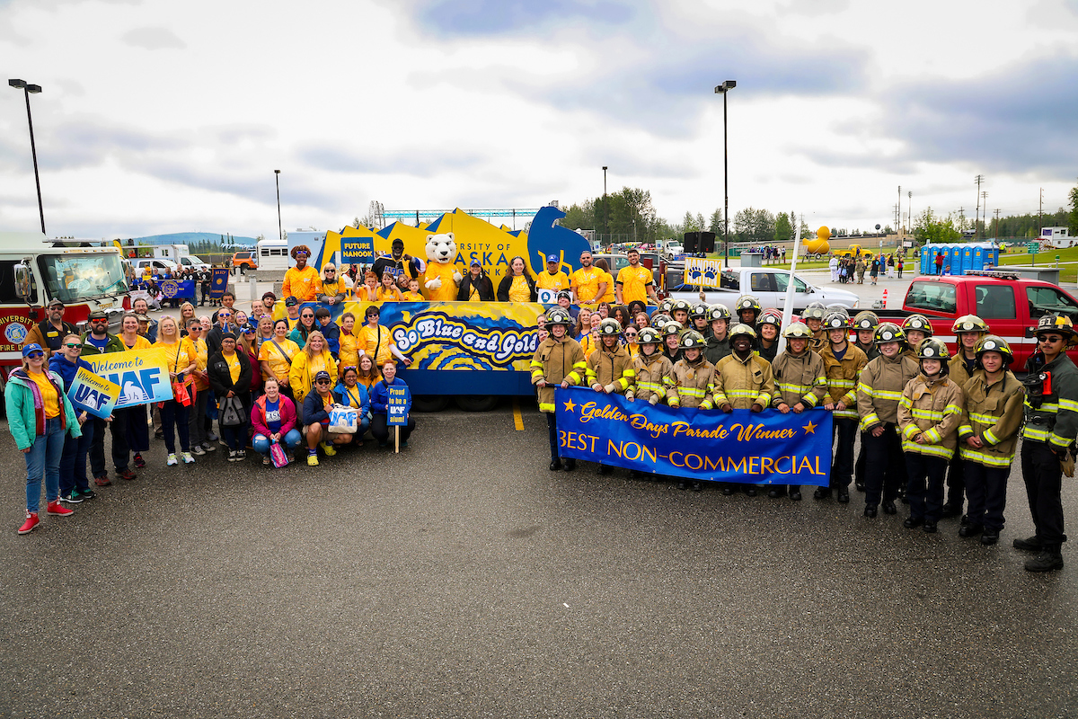 Participants of UAF's 2023 Golden Days Parade march gather for a group photo before walking through downtown Fairbanks.