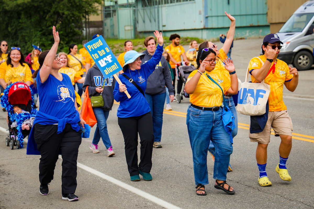 UAF staff and alum wave to the crowd while dancing through the streets of downtown Fairbanks during the 2023 Golden Days Parade march.