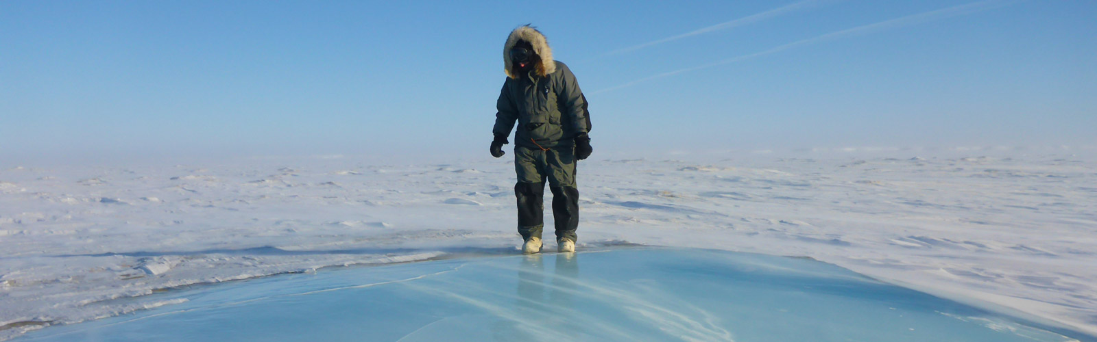 Researcher standing on frozen lake ice.
