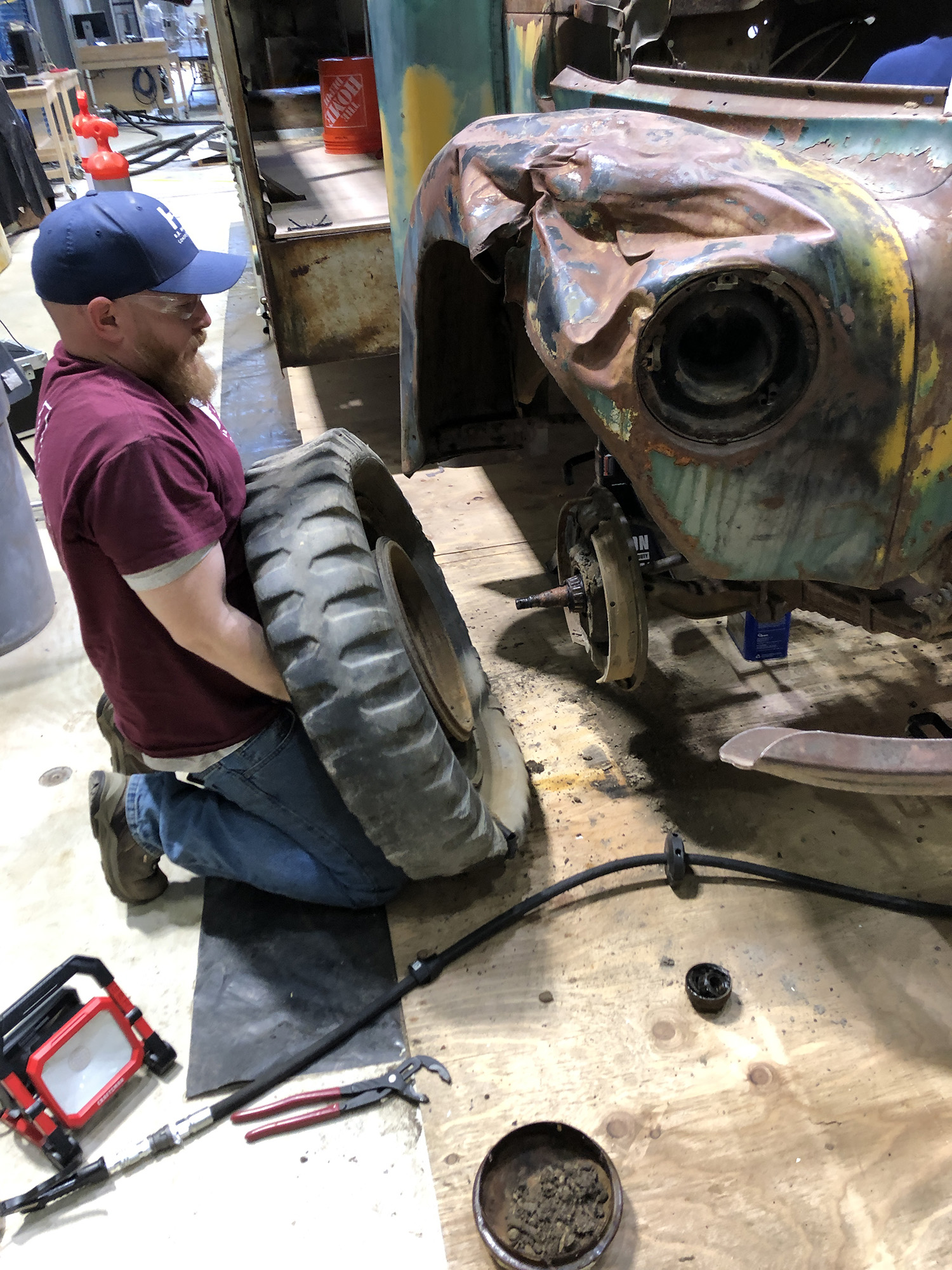 man removes wheel from bus axle
