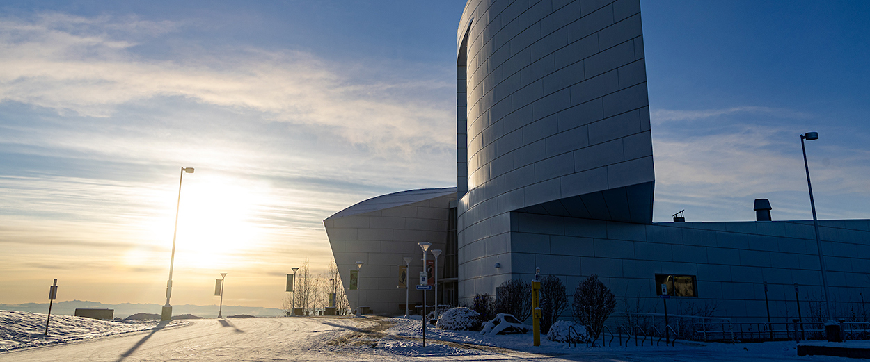 The sun sets over the west ridge of the Troth Yeddha' campus in Fairbanks. The UA Museum of the North is in the foreground.