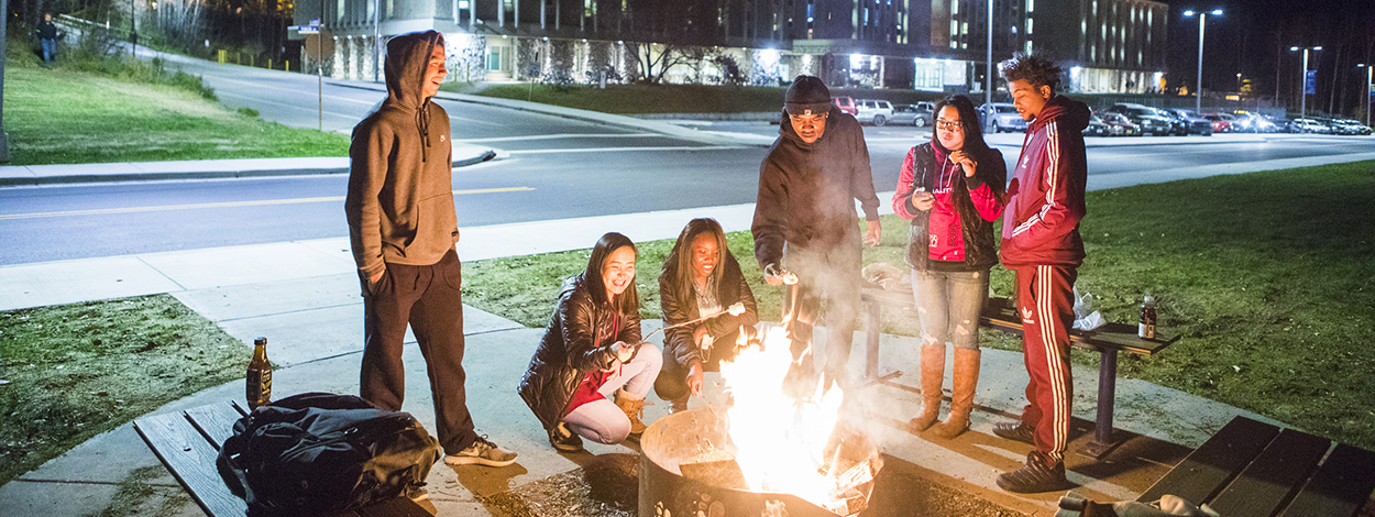 UAF students roast marshmallows around a fire pit on campus