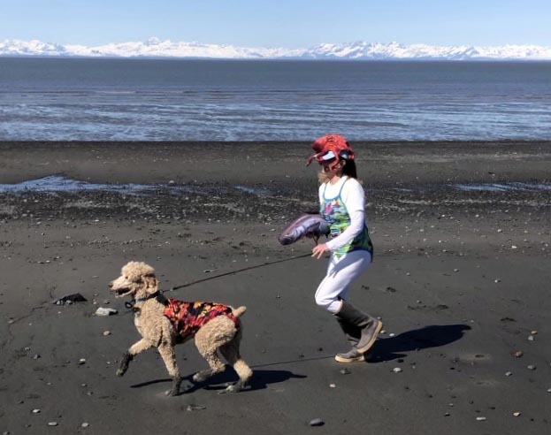 Woman runs on a beach with a dog