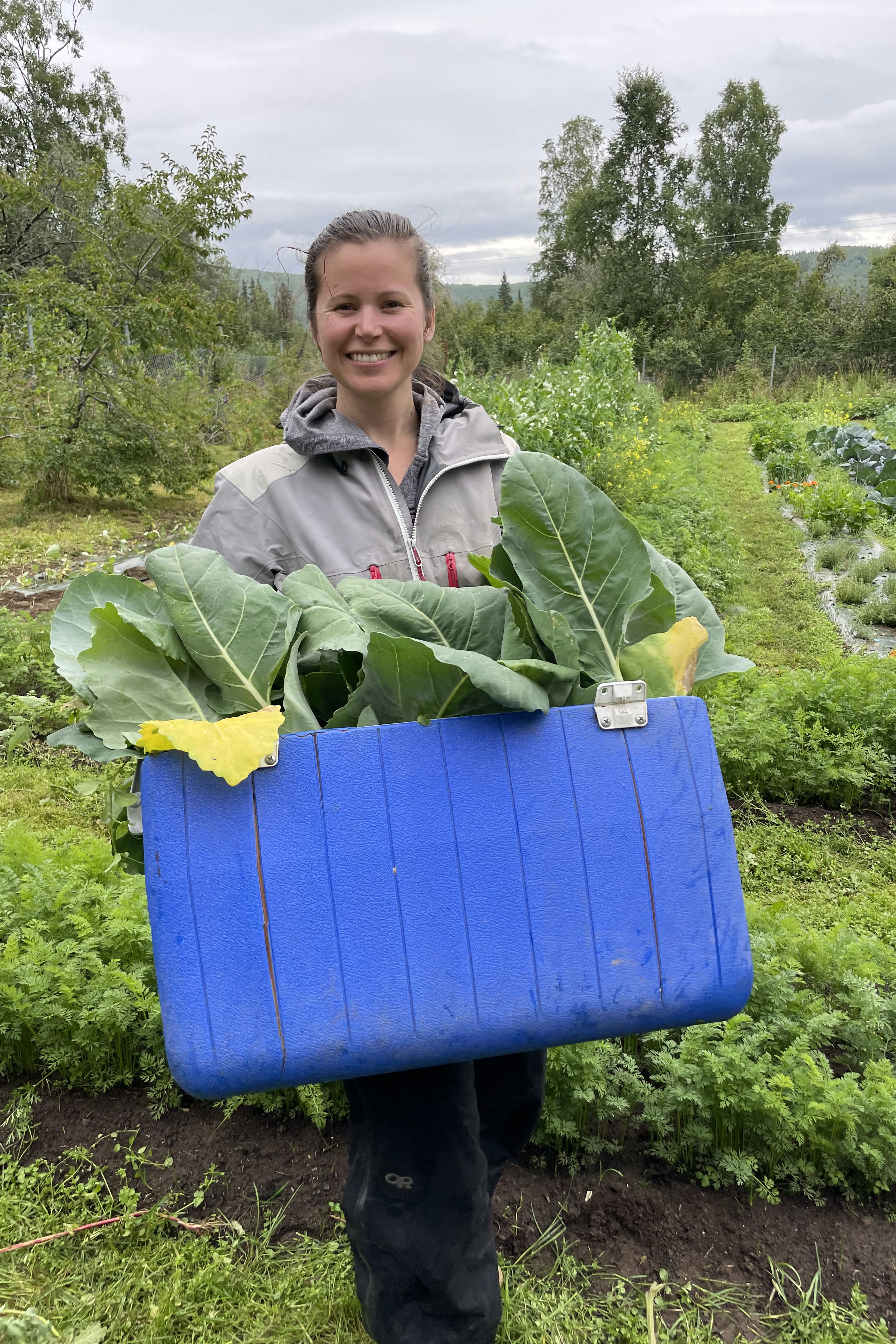 Woman holding a cooler filled with produce.