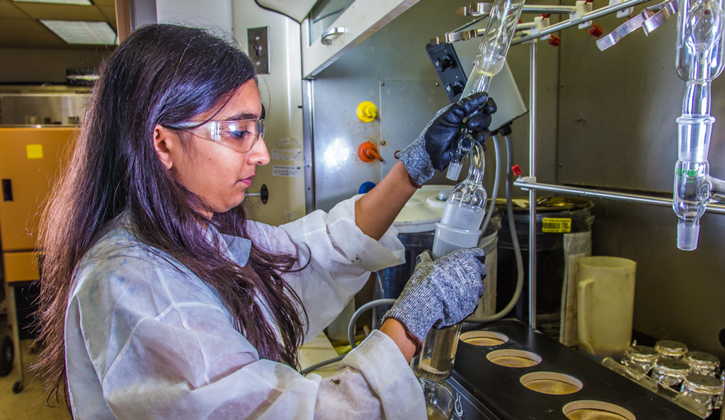 Graduate student sets up apparatus for a procedure in UAF's Petroleum Development Lab