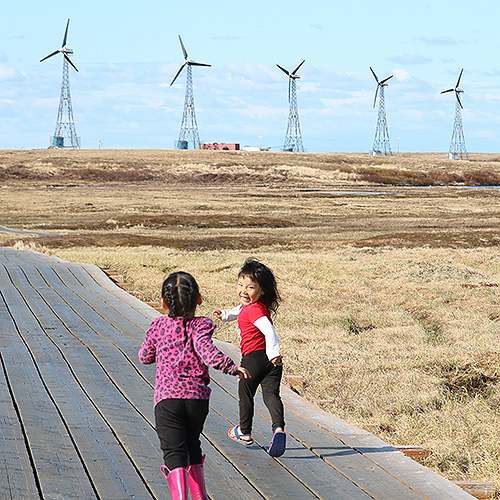 Children running with wind turbines in the background