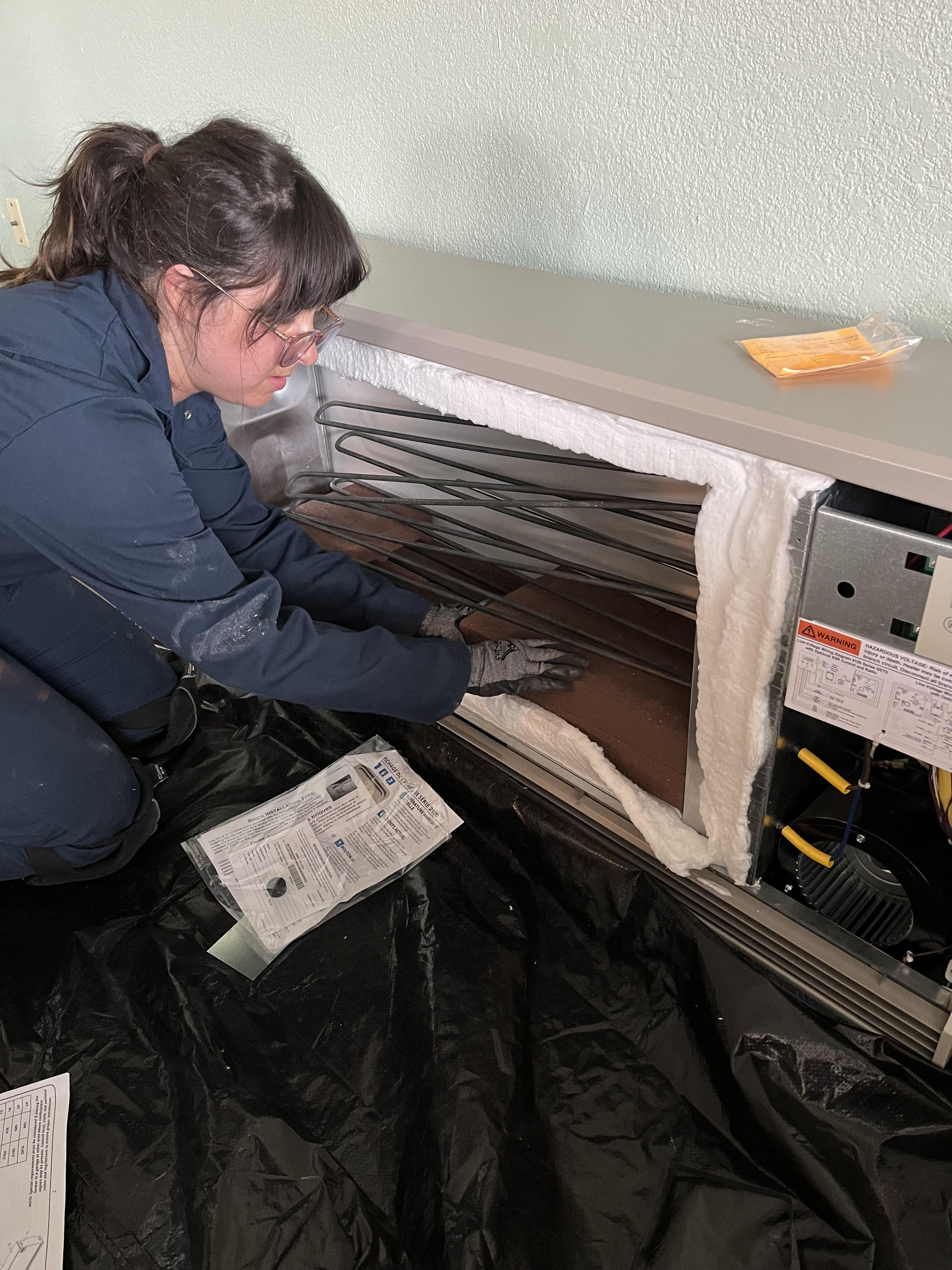 Alana Vilagi stacks bricks around the electric resistance elements of an electric thermal storage heater 