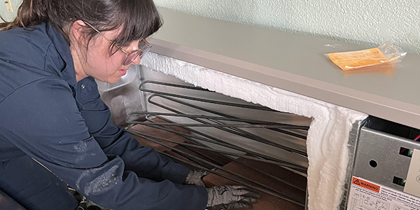 Alana Vilagi stacks bricks around the electric resistance elements of an electric thermal storage heater.