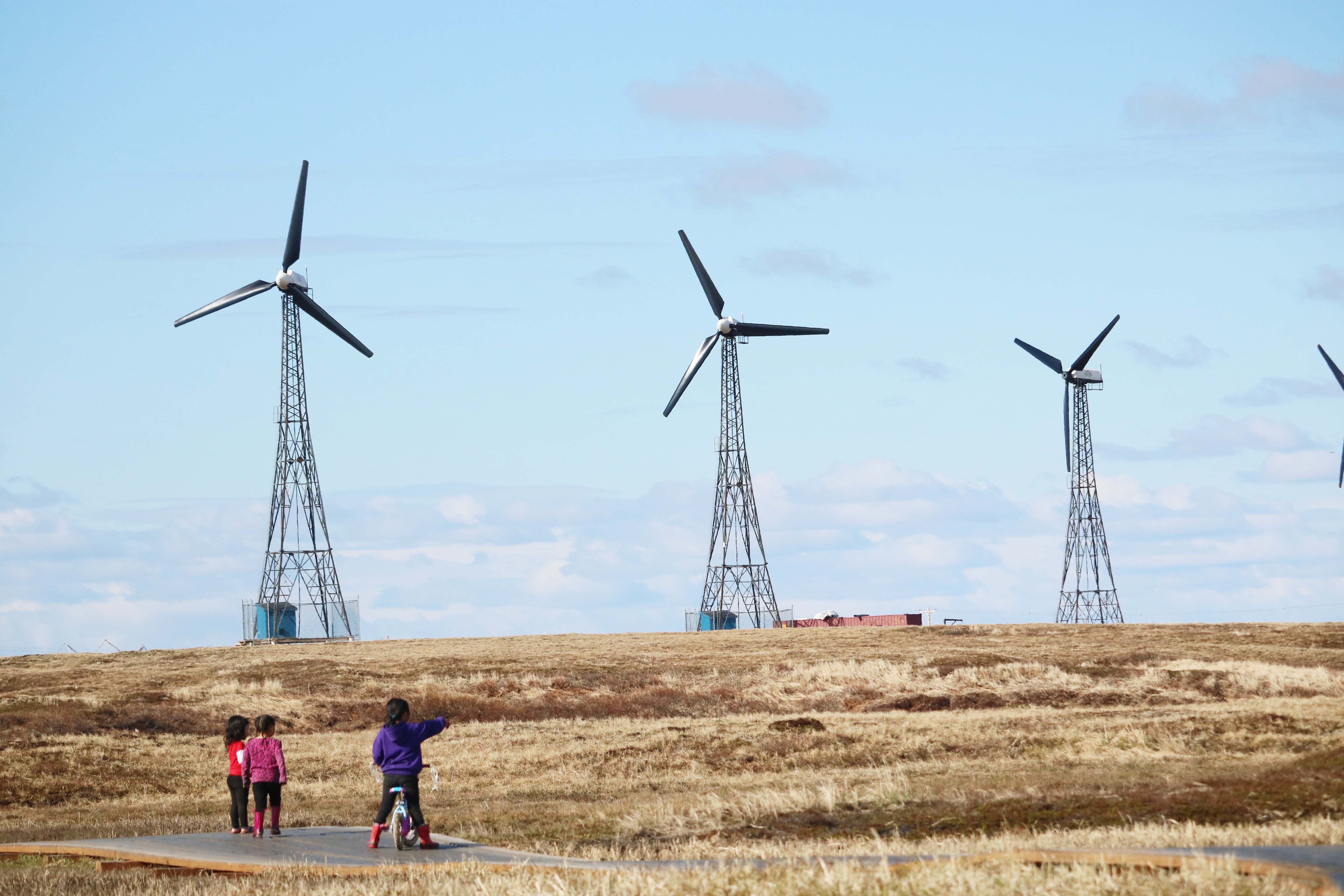 Children in Kongiganak on Alaska's Yukon-Kuskokwim Delta look out at wind turbines that provide power the remote community.