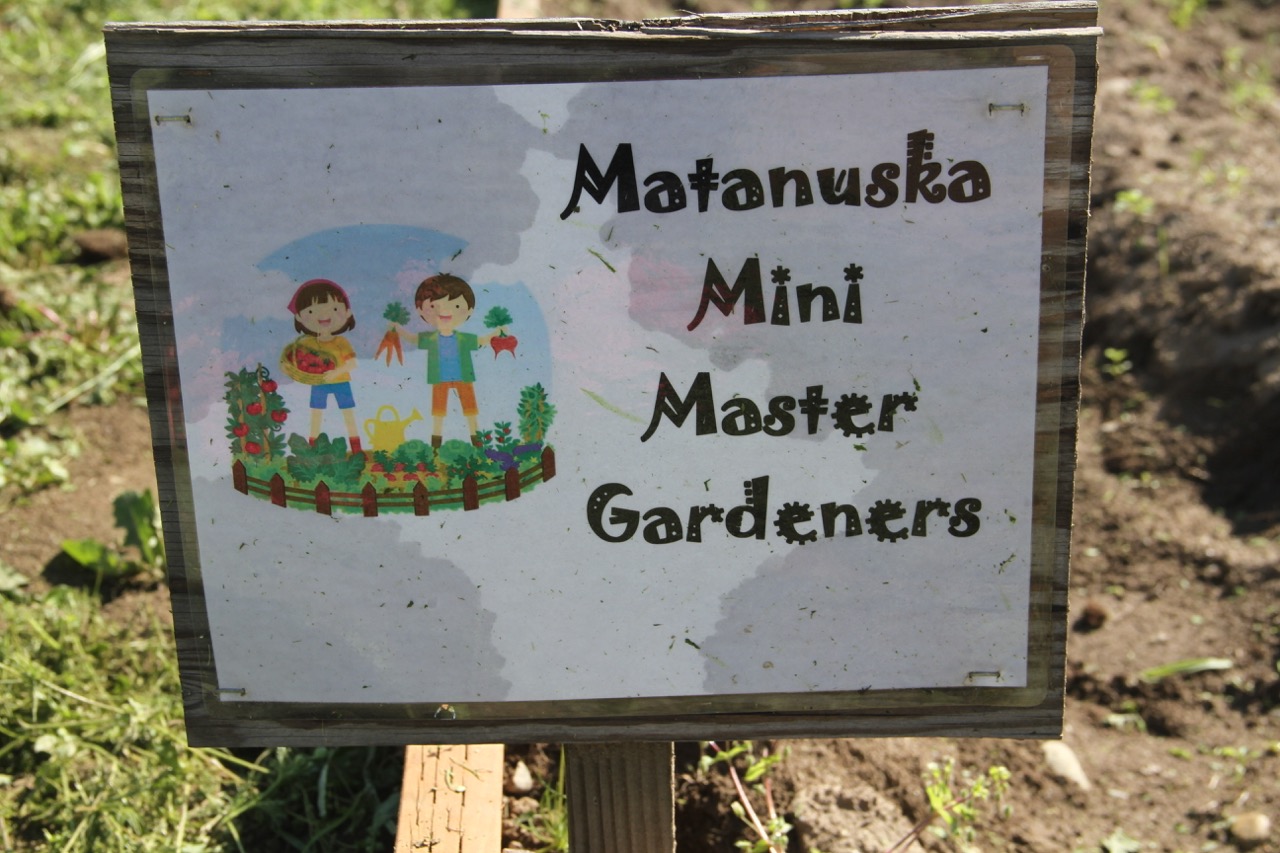 A small wooden sign saying "Matanuska Mini Master Gardeners" on it