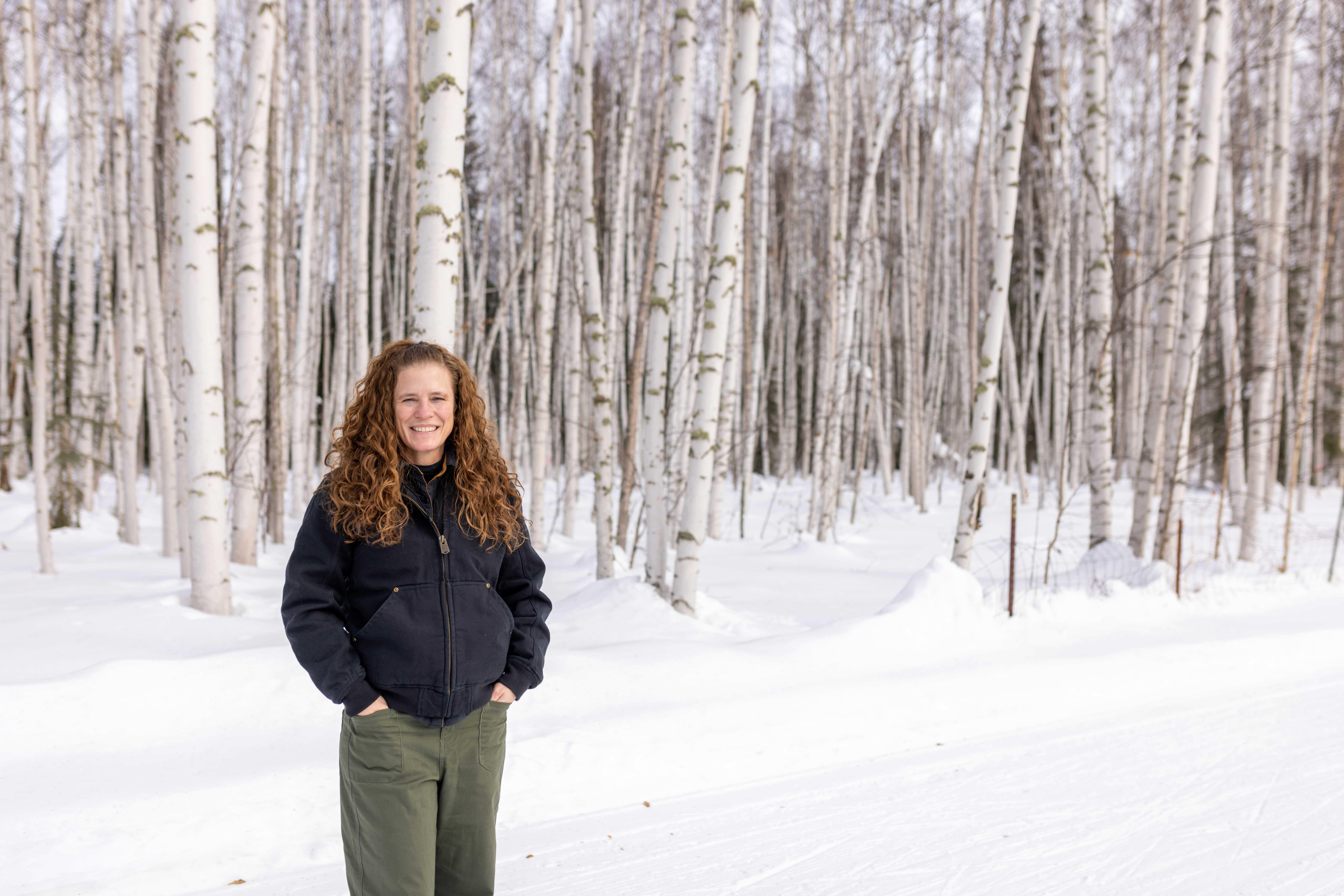 Jessie Young-Robertson stands in front of a snowy birch forest