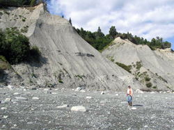 Contract geologist Dick Reger stands at the base of thick deposits of glacioestuarine sediments exposed in coastal bluffs near Granite Point, western Cook Inlet.