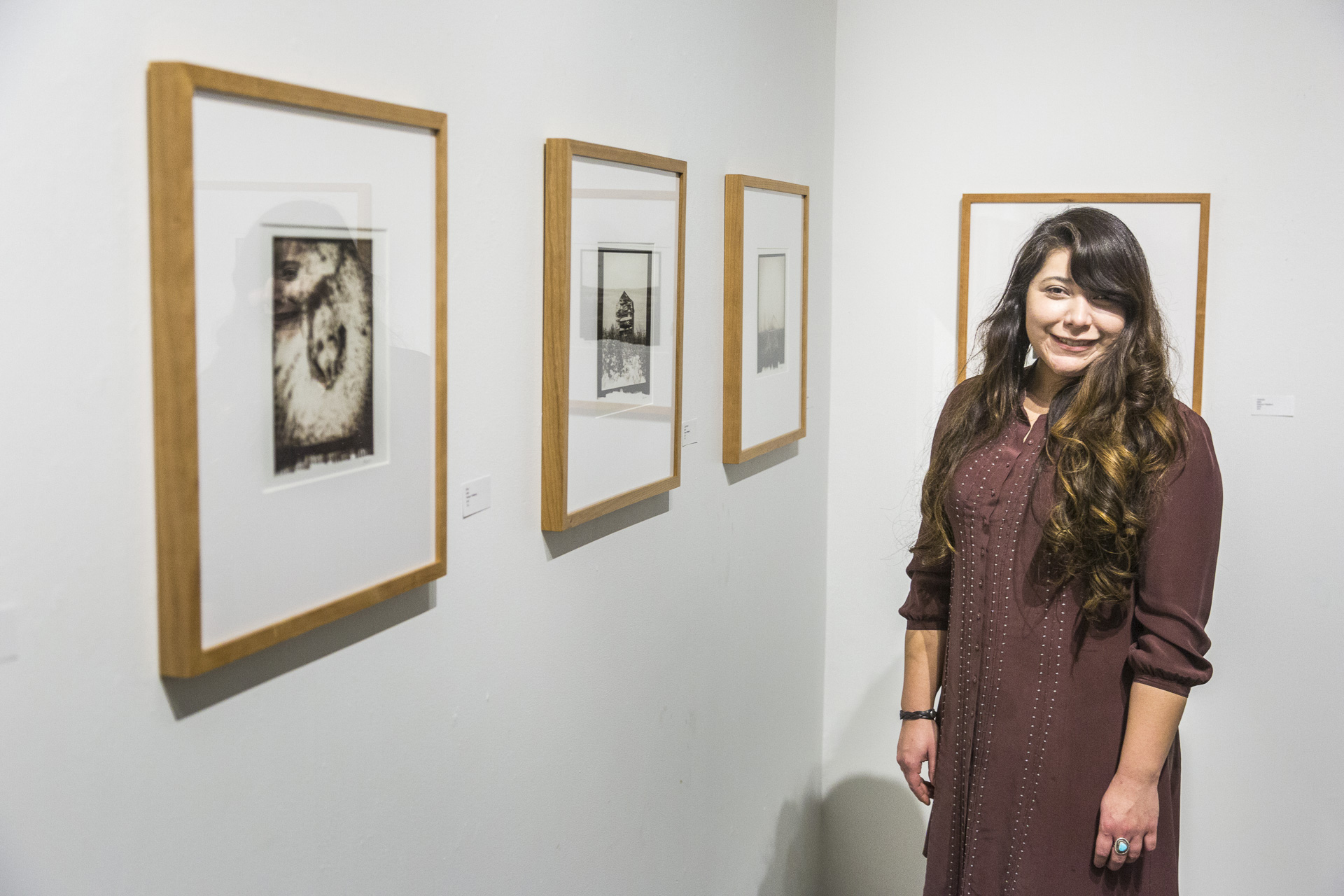 Photography MFA student Alyssa Enriquez stands next to her thesis show: Nome as Place at Well Street Art Gallery | UAF Photo by JR Ancheta