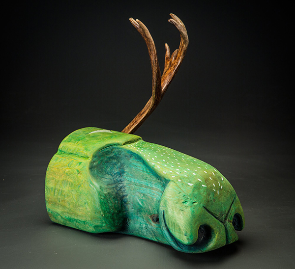 A carving of a moose nose colored green with an antler protruding from the top