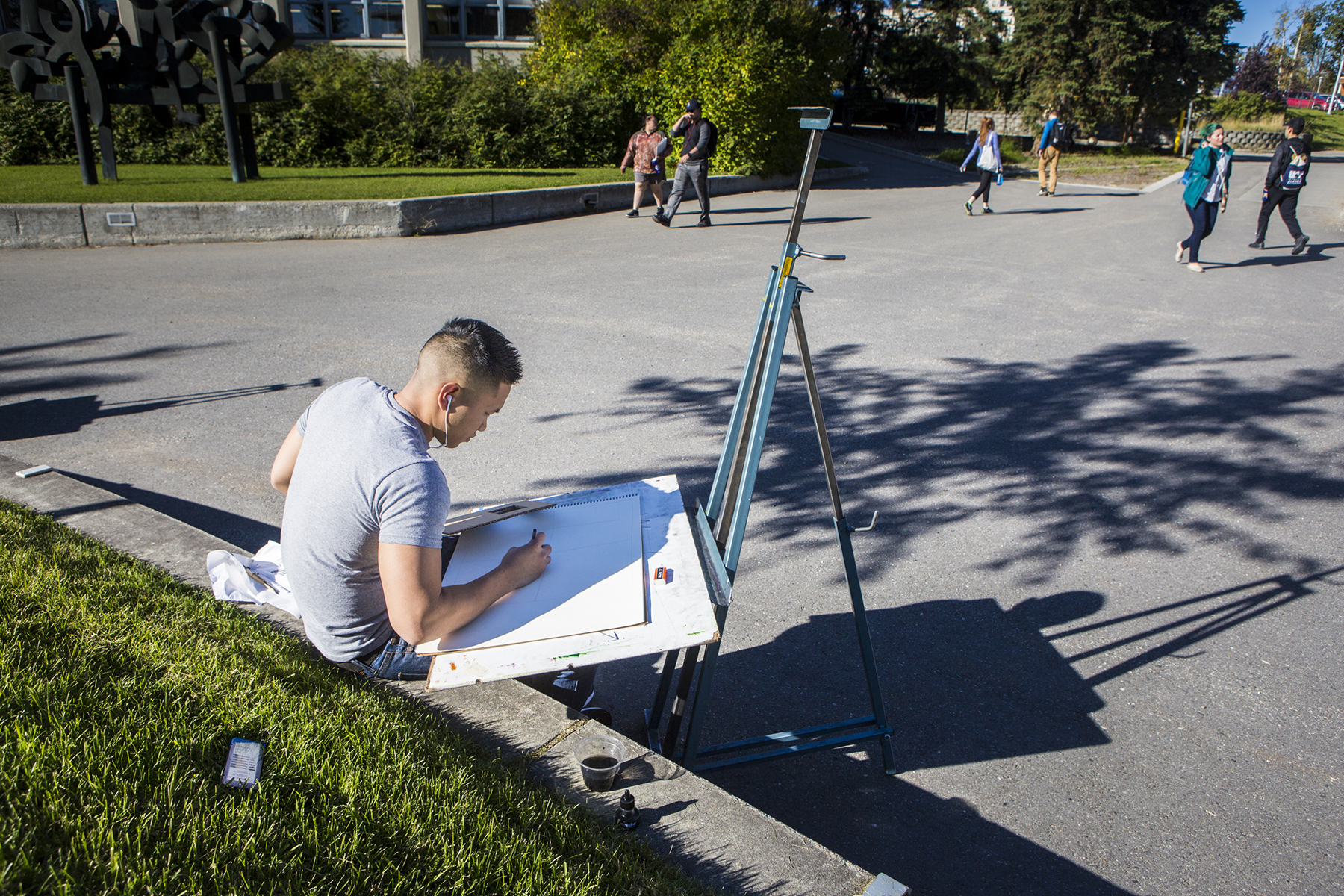 Joaquin Cruz sits outside of the fine arts complex working on an art project for class on Monday, September 10th 2018. | UAF Photo by Sarah Manriquez