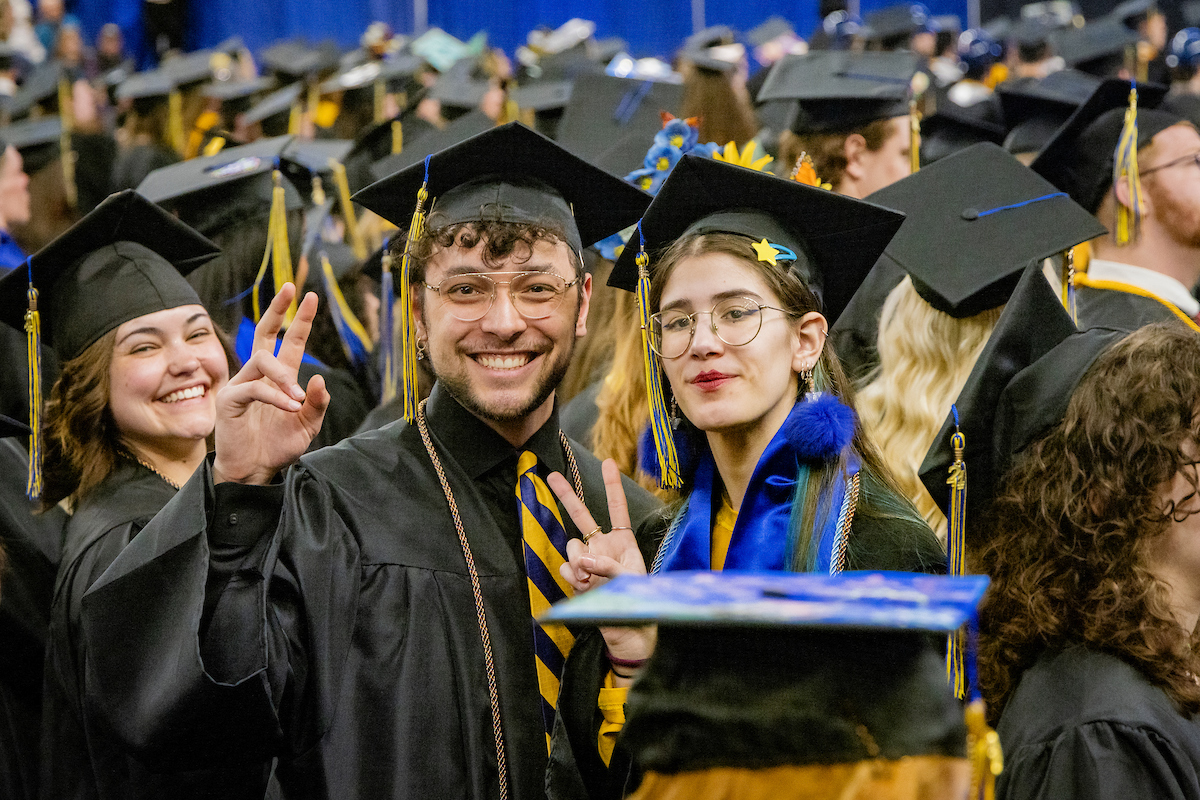 UAF CLA graduates Kyle Augustines and Marina Gonzalez take a photo together at the start of the 2024 Spring Commencement Ceremony at the Carlson Center, 5/4/24. (UAF photo by Leif Van Cise)