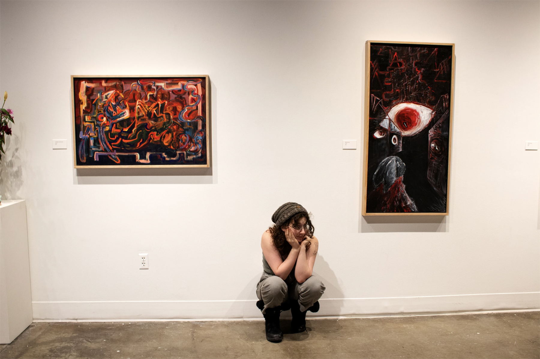 Chana Stern poses under two paintings at the reception for "Pilgrimage of the Revenant", courtesy of the artist