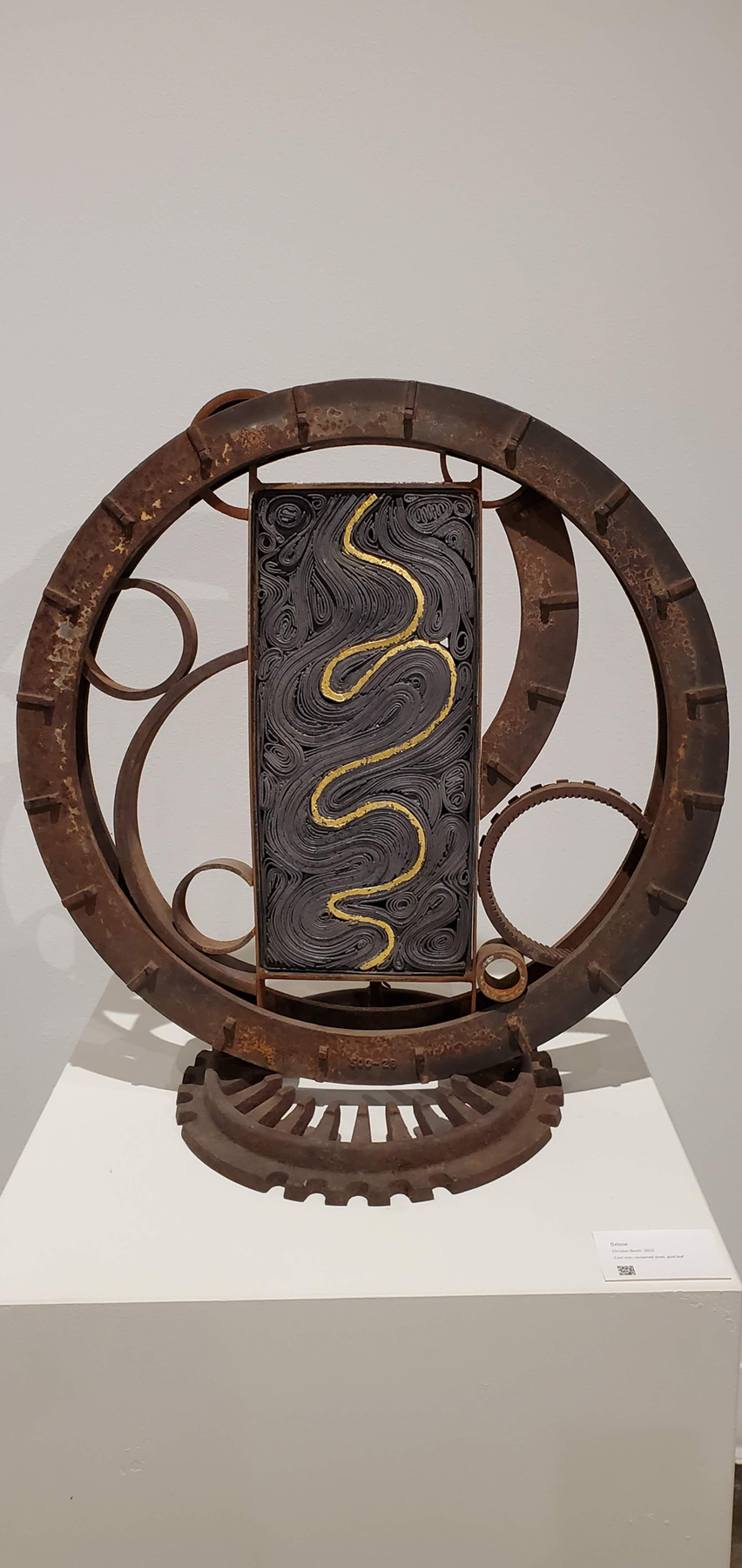 A winding topographic plate with winding gold leaf inside a steel whwwl, image courtesy of the artist