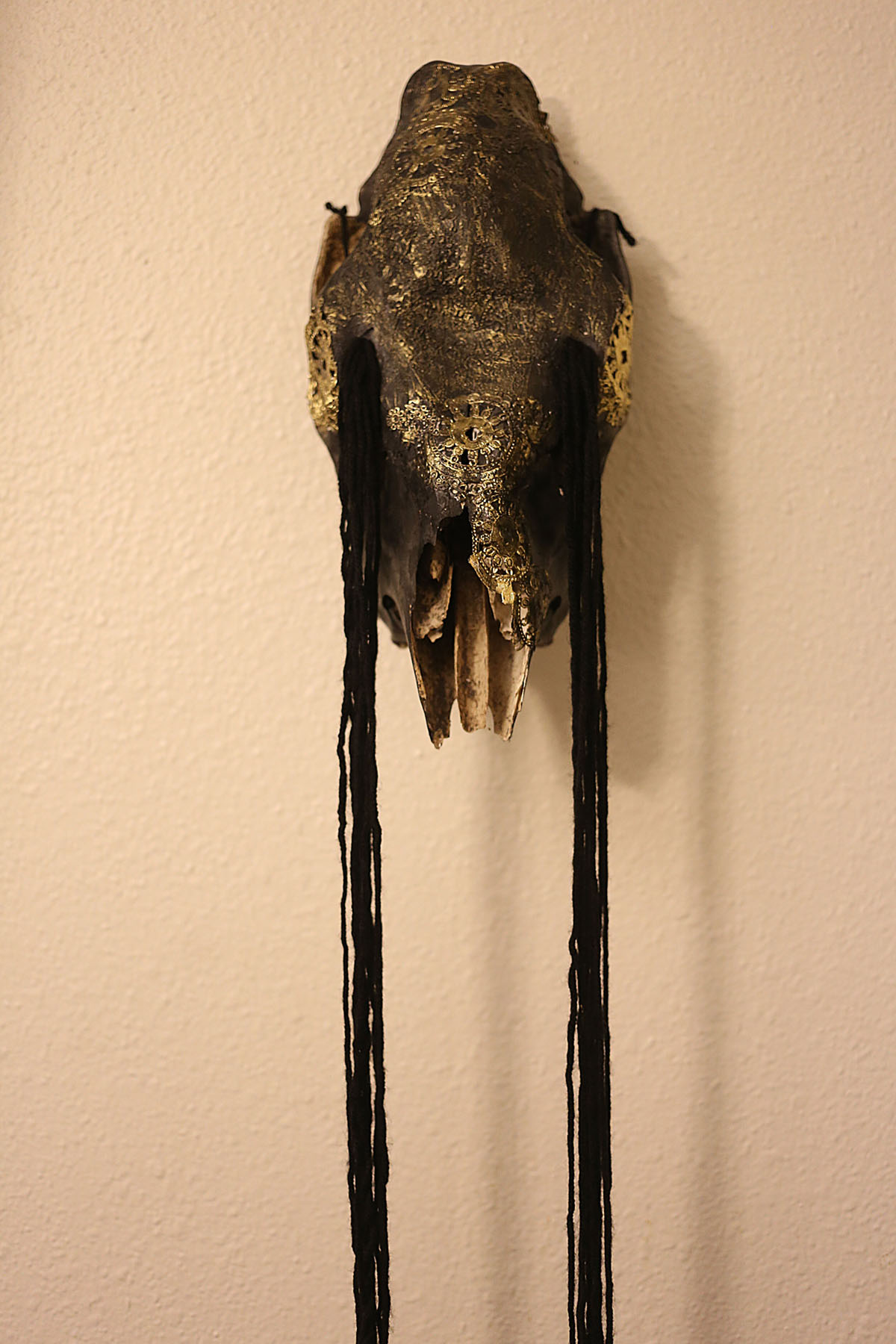 Carved skull with selective gold paint and black thread adornments. Image courtesy of Indi Walter