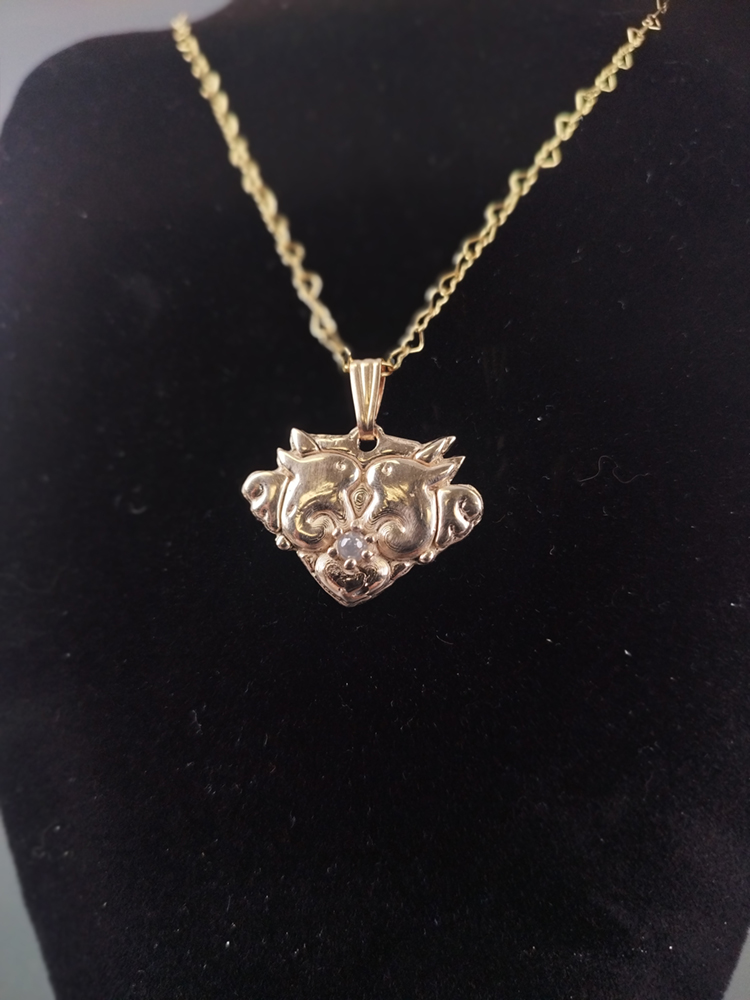 detailed shot of gold pendant featuring bunnies and a small stone. Image courtesy of the artist