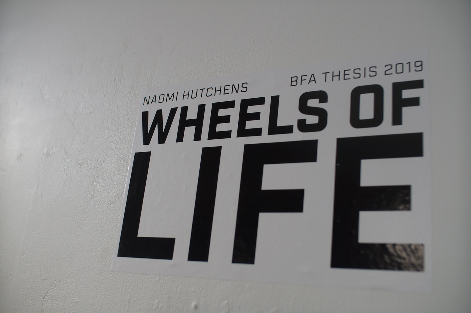 Wheels of Life show title on the wall at Naomi Hutchquist's BFA thesis exhibition at Well Sreet Art Gallery in 2019. Image courtesy of Naomi Hutchquist