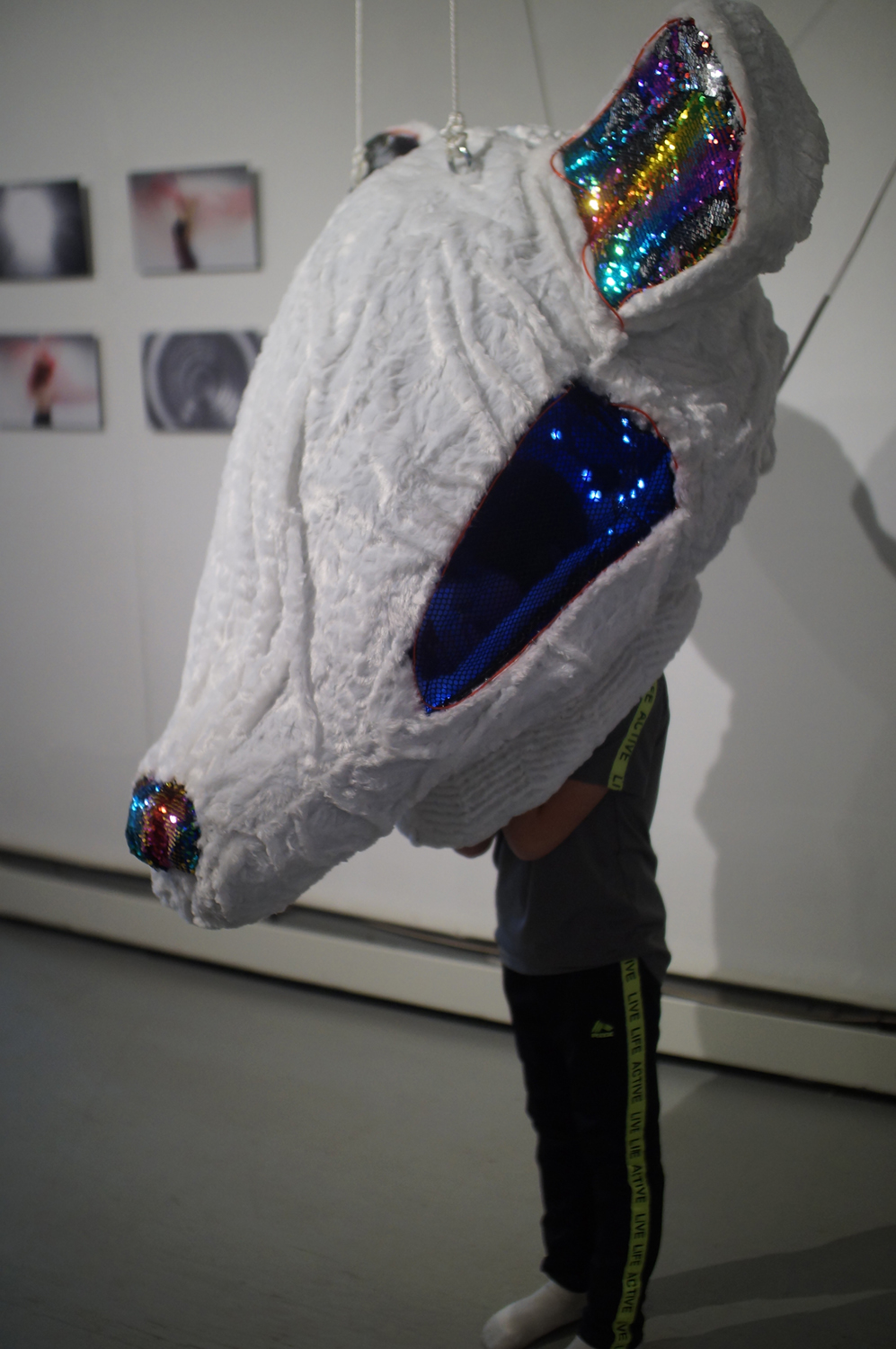 A child standing with their head in the mouse mask of the Who Are You? Who Am I? piece in the exhibit. Image courtesy of Naomi Hutchquist