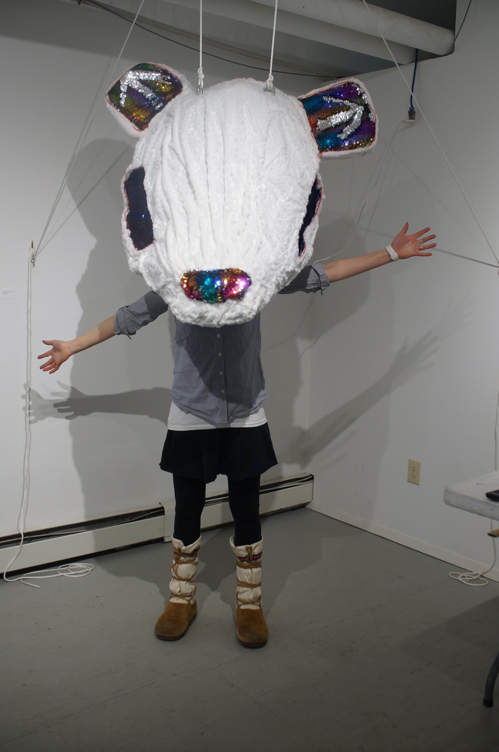 Naomi poses in the large white mouse mask that is the Who Are You? Who Am I? piece of the exhibit. Image courtesy of Naomi Hutchquist