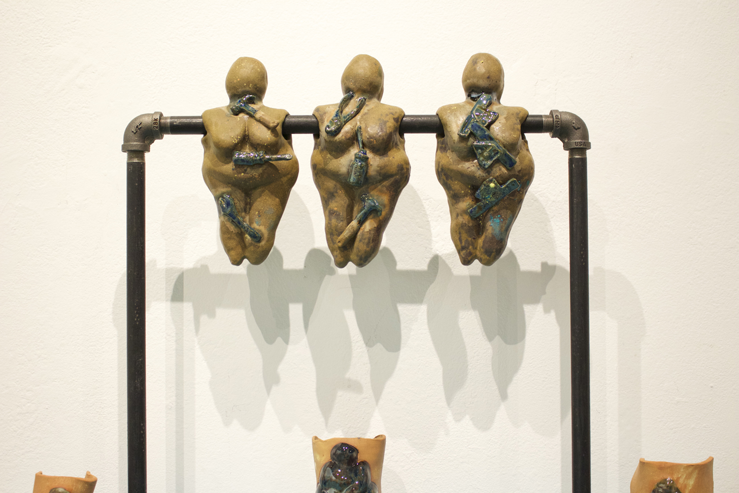Three ceramic goddesses on a steel pipe. Image courtesy of Olena Ellis