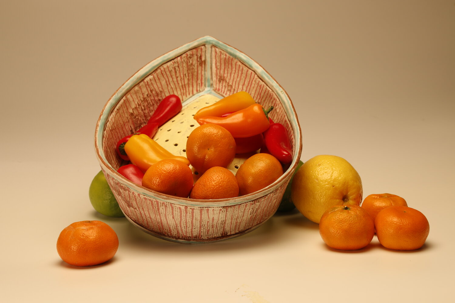 An almond shaped ceramic colander filled with fruit, image courtesy of the artist