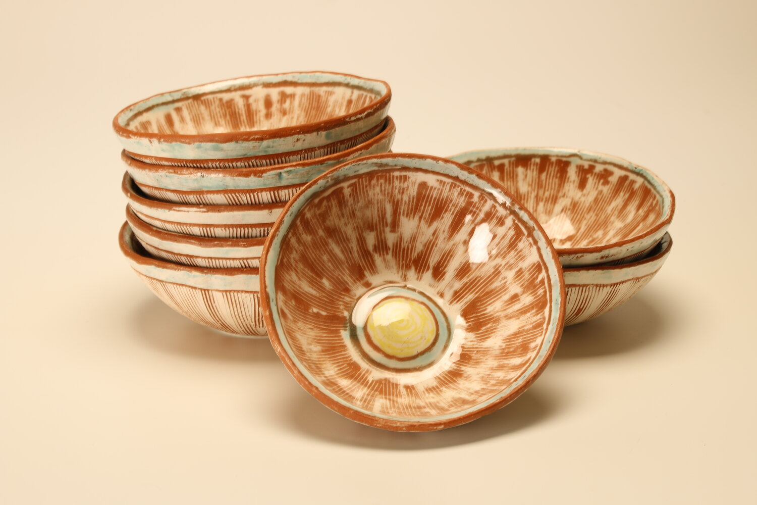 Stacks of everyday ceramic bowls with inlaid white slip and sgraffito, image courtesy of the artist