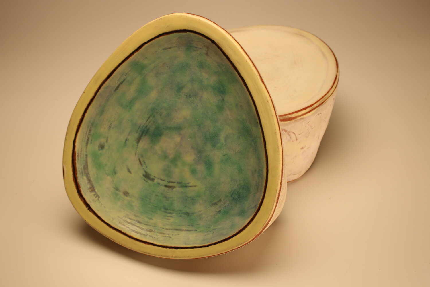 A pair of triangle shaped dishes; one with a blue green interior is propped up, image courtesy of the artist