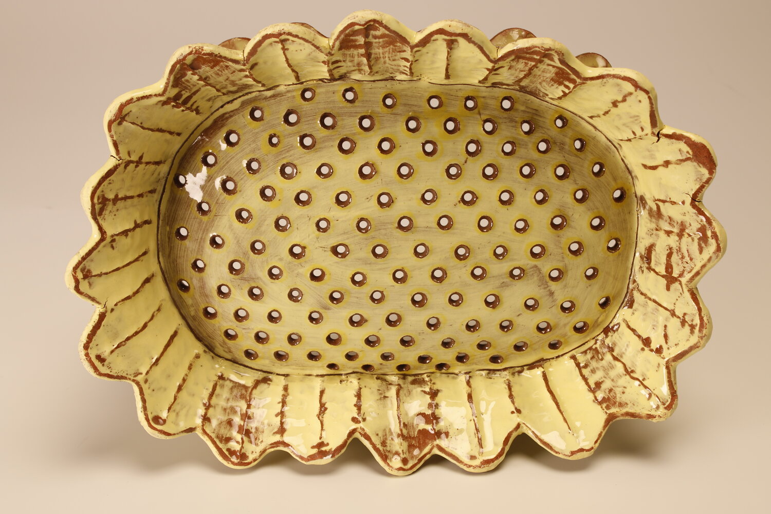 A pale yellow ceramic colander in the shape of a sunflower, image courtesy of the artist