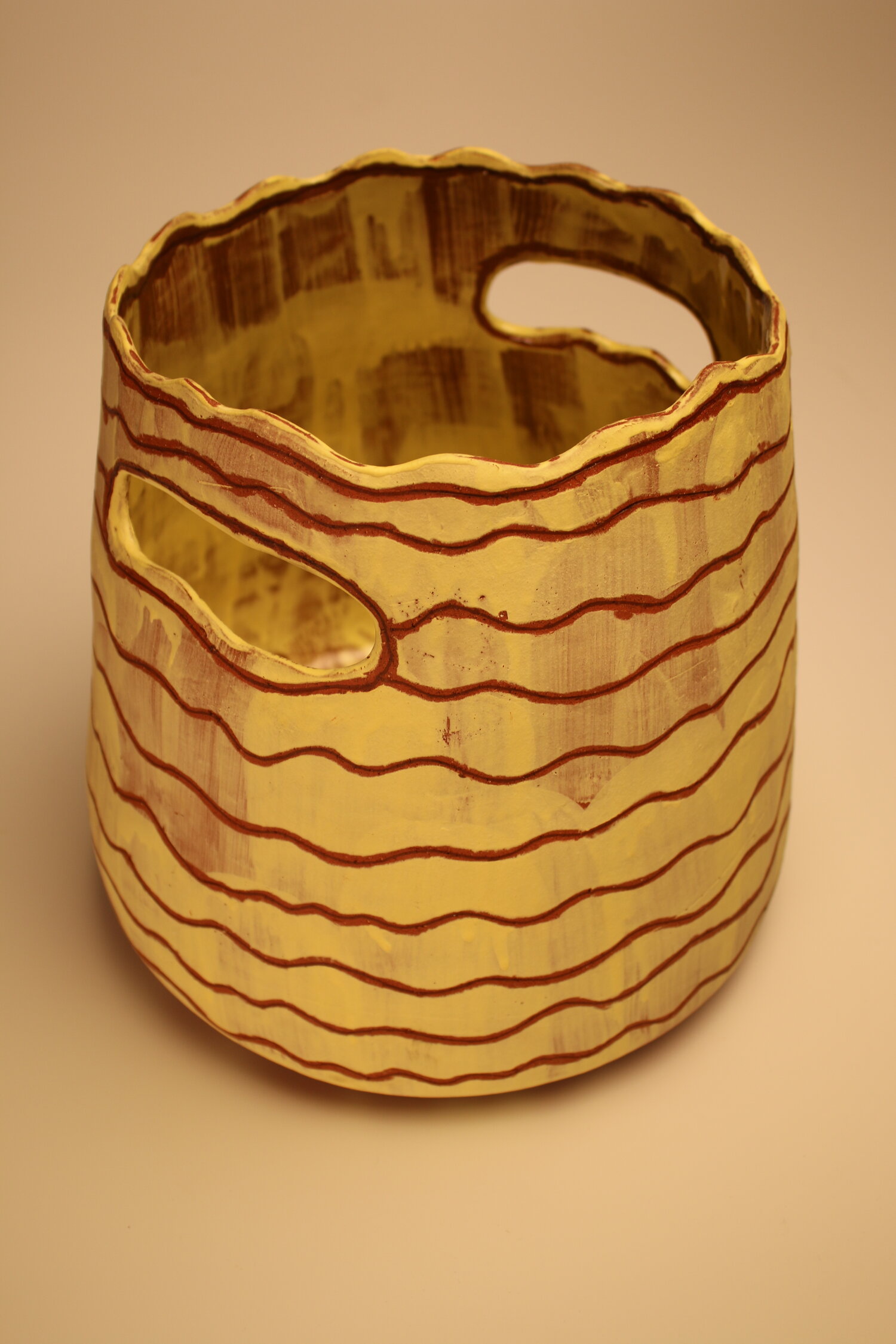 large yellow ceramic basket with thin brown inlaid stripes and handles, image courtesy of the artist