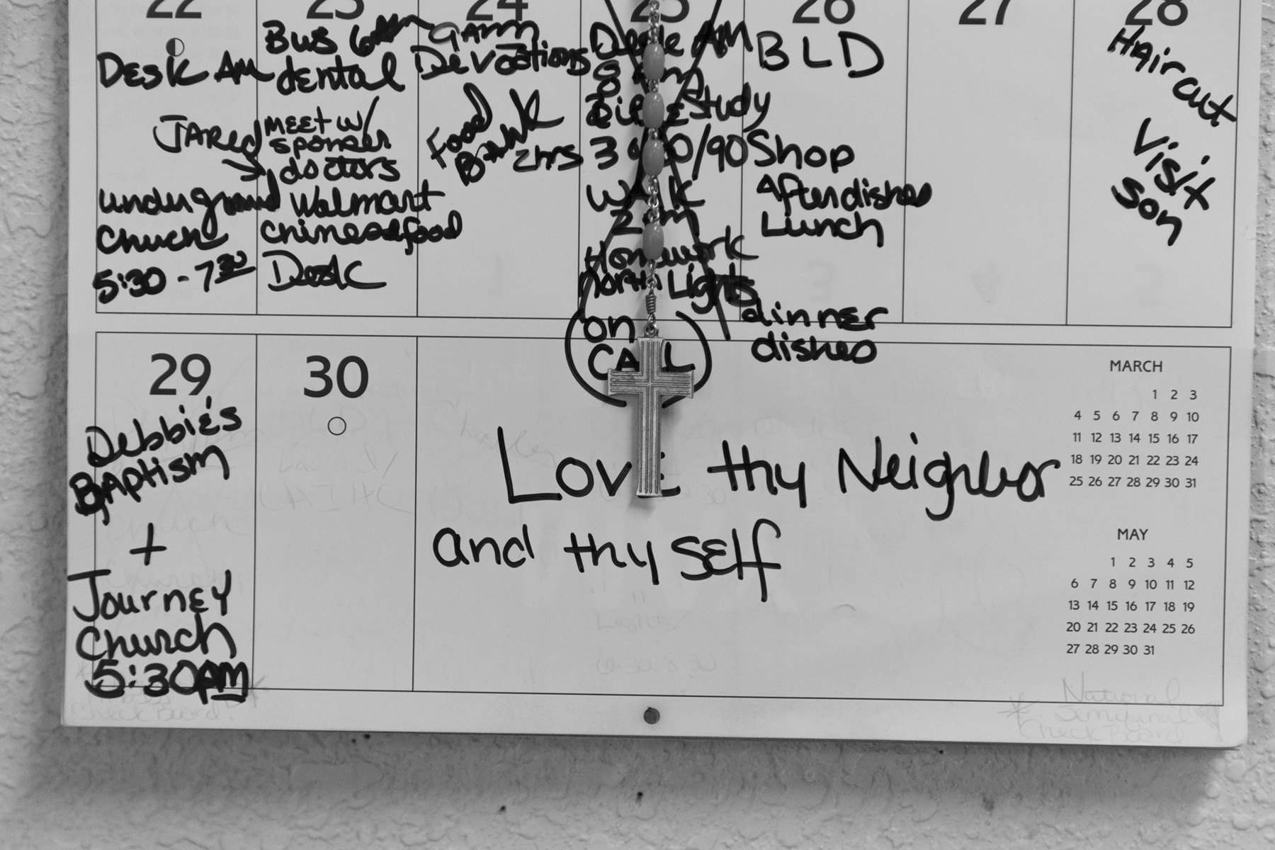 Felicia Cavanaugh’s April calendar hangs on her wall beside her bed along with her rosary and a written reminder from the bible to “Love thy neighbor and thy self,” on April 28th 2018. Courtesy of the artist