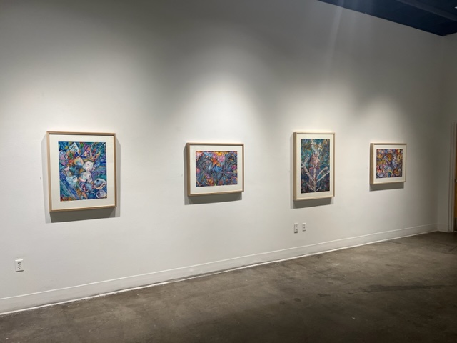 Framed paintings hang on the wall of the UAF Art Gallery during Susan Andrews' MFA exhibition, The Cascade Effect. Image courtesy of the artist