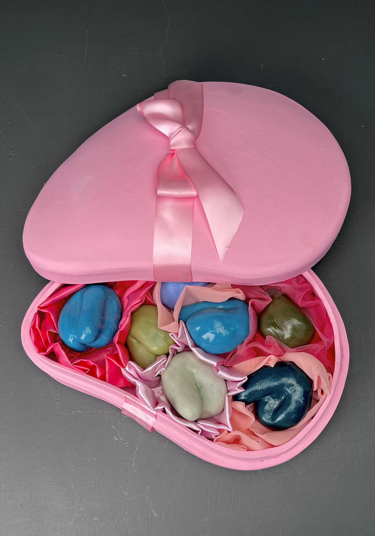 Conceptual ceramics piece showing the coddling of the male ego in a pink heart box, courtesy of the artist