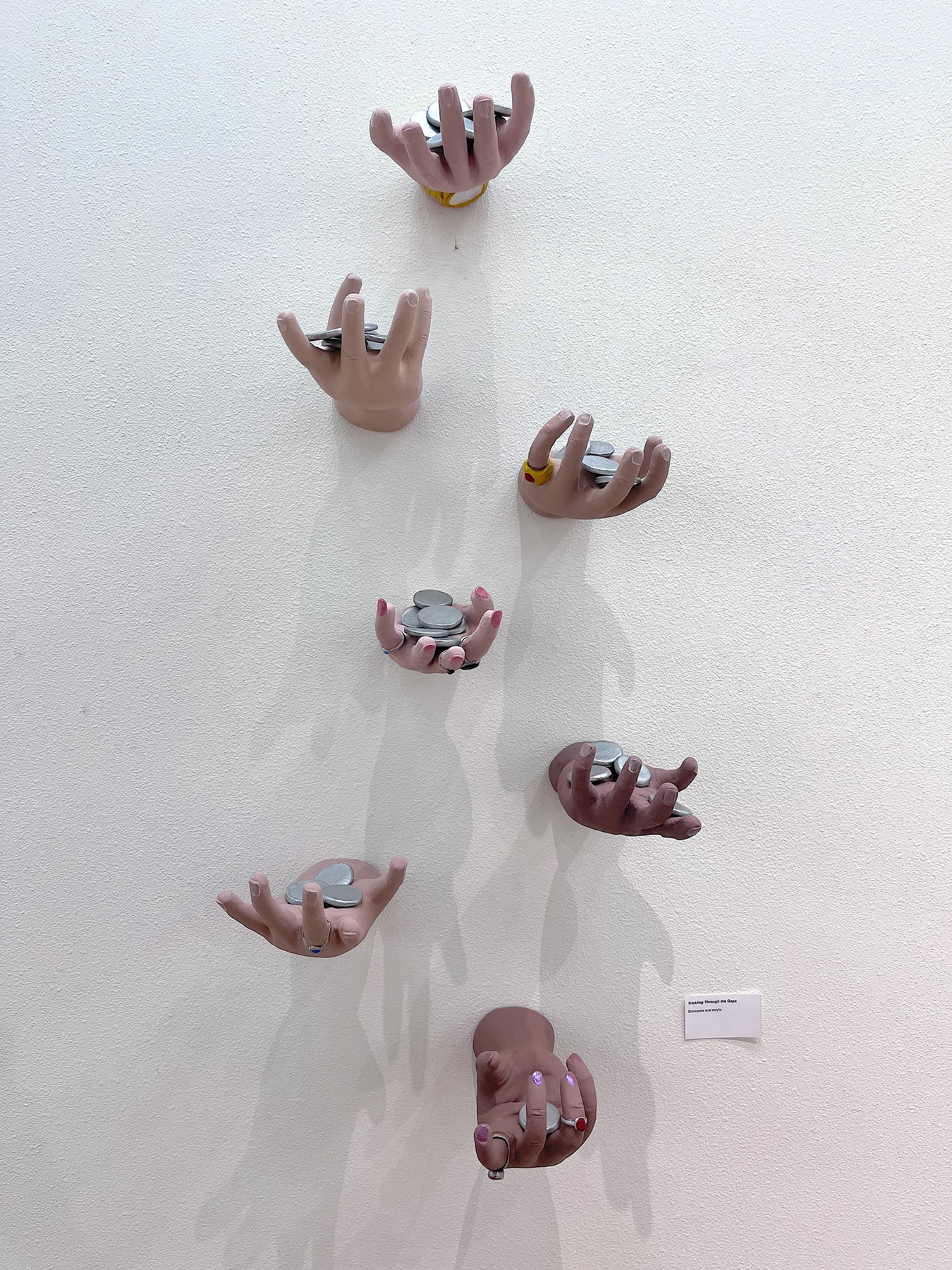 Hands affixed to the wall holding coins, courtesy of the artist