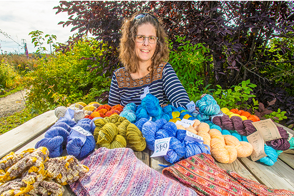 Melissa Shippey sits in front skeins and balls of yarn. 