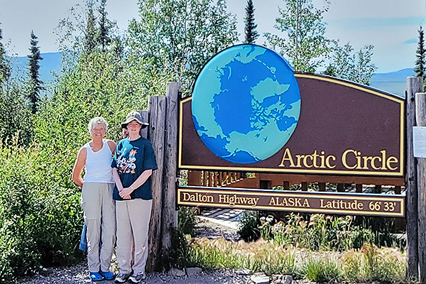 Carol Swarts and a colleague stand by the Arctic Circle sign on the Dalton Highway during their ground squirrel research trip.