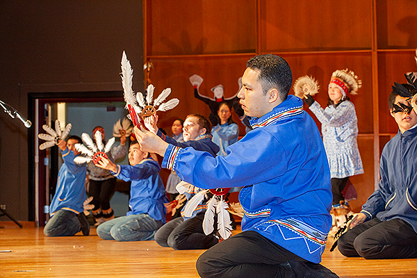 Dancers in blue kuspuks kneel while performing with feathered hand fans at the 2009 Festival of Native Arts. UAF photo by Todd Paris.