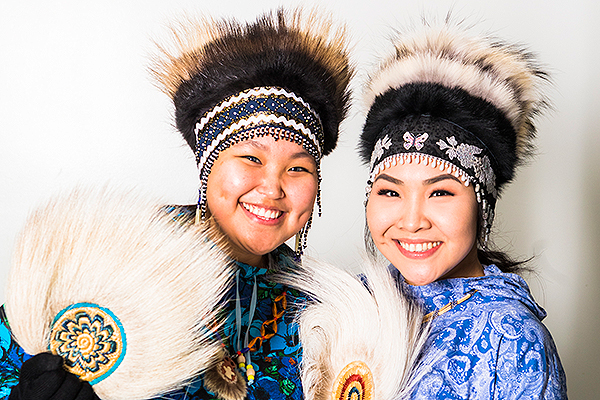 Two young women pose in traditional fur headdresses while holding fur-trimmed dance fans at the 2018 Festival of Native Arts. UAF photo by JR Ancheta.