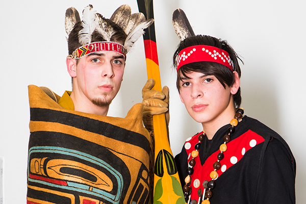 Two young men in traditional attire pose with a decorated paddle at the 2018 Festival of Native Arts. UAF photo by JR Ancheta.