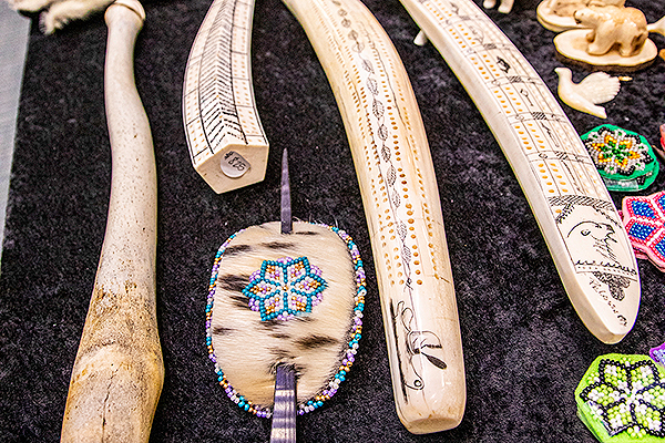 Alaska Native arts and crafts items, including walrus tusk cribbage boards and a beaded sealskin hair barrette, are displayed at the 2024 Festival of Native Arts. UAF photo by Marina Santos.