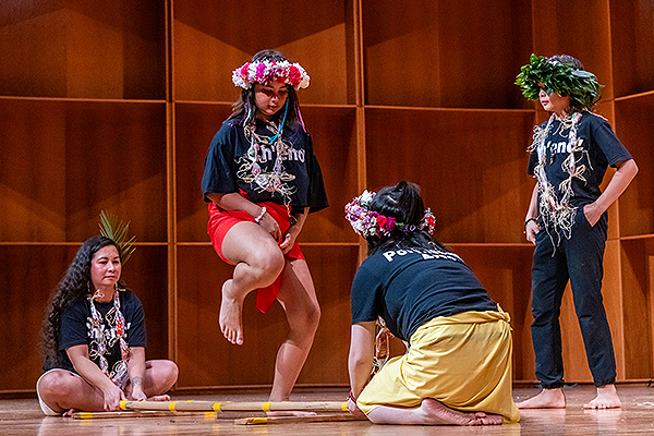 Children and young adults perform a dance using sticks on the stage floor during day one of the 2024 Festival of Native Arts. UAF photo by Marina Santos.