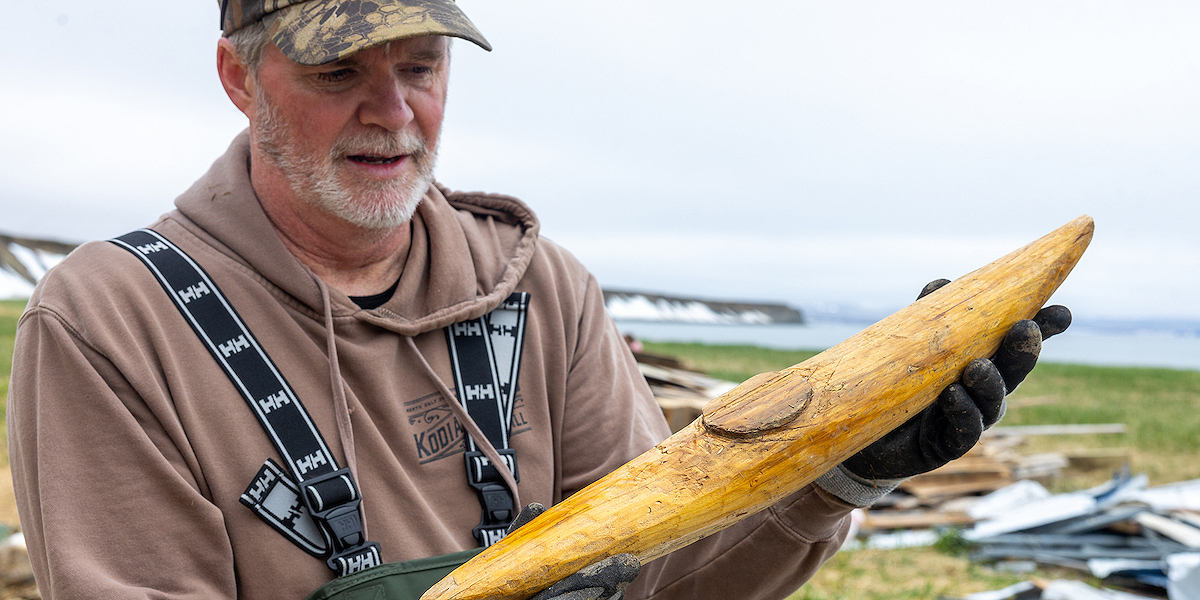 UAF photo by Eric Engman. John Pennington displays a hand-carved wooden kayak found as the volunteer crew cleaned up debris.