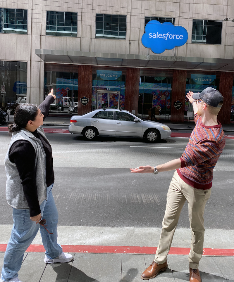 Two students pointing at Salesforce building from the sidewalk