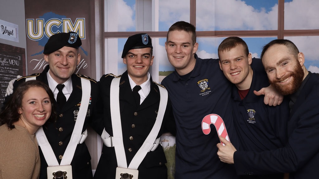 Five men and one woman stand in ROTC uniform at a photobooth.