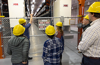 People in hardhats standing in a warehouse.