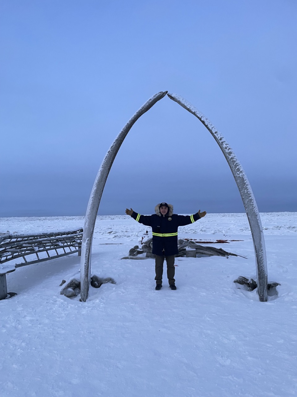 Anthony stands beneath an arch made of bowhead whale jawbones in Utqiagvik for the Rural Resilience Workshop in 2023.